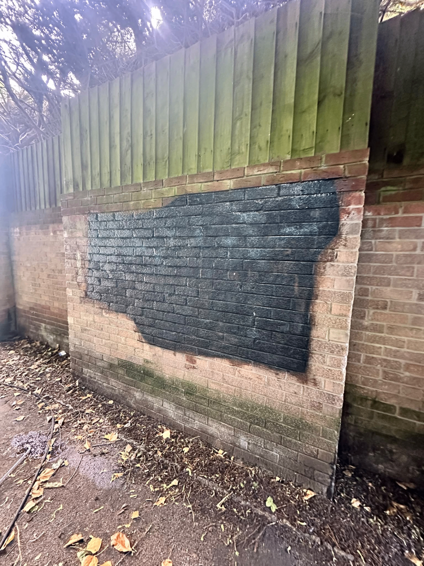 Brick wall with heavy black spray paint graffiti before professional removal