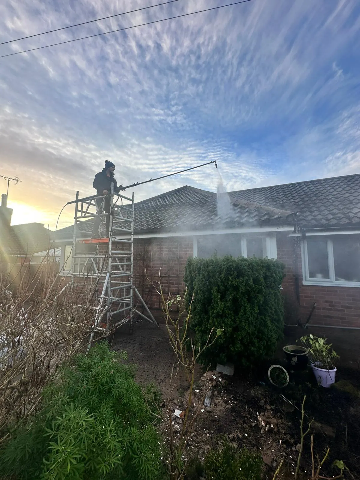 Marsh Exterior Cleaning operative carrying out roof cleaning work at sunset in Liverpool