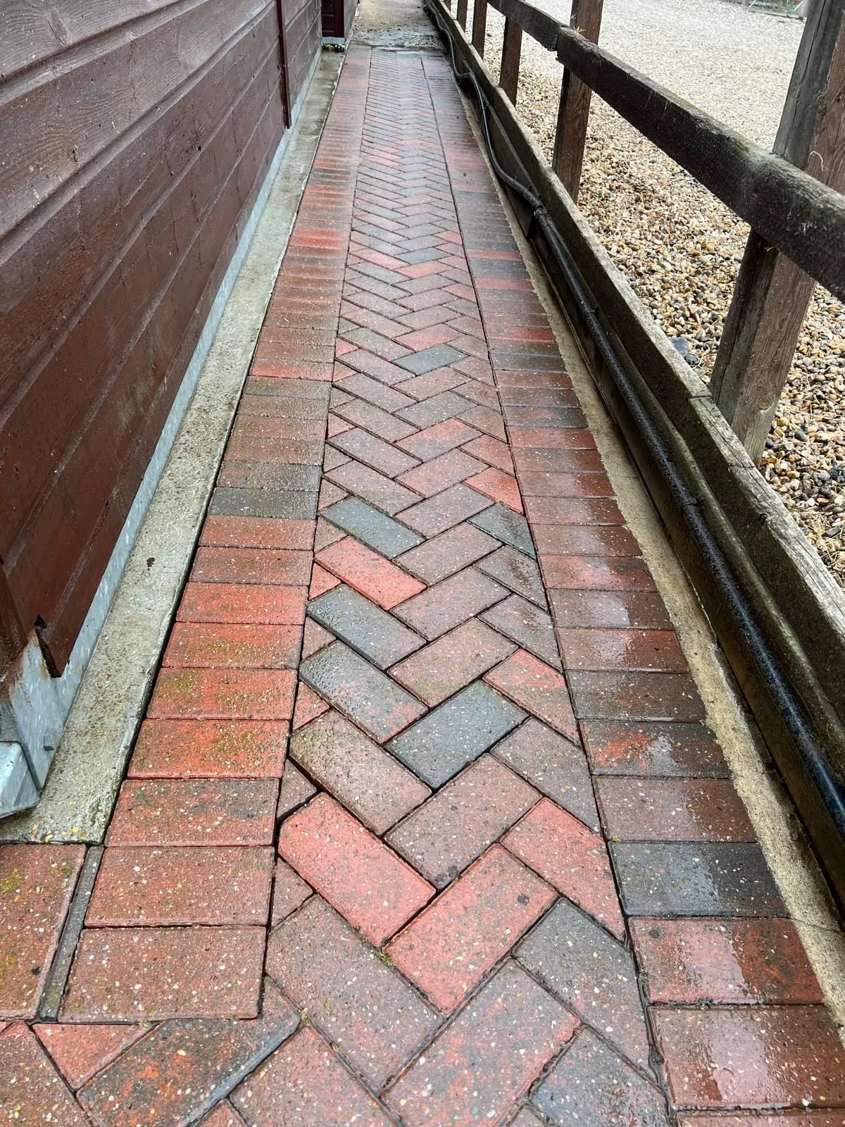 Clean herringbone block paving stable path restored to original red colour after professional cleaning