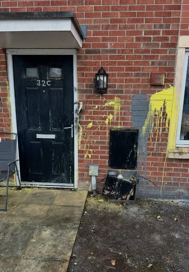 Yellow paint vandalism splattered across brick wall and front door before professional paint removal