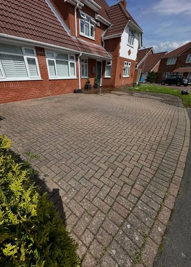 Faded block paving driveway with moss and algae before professional pressure washing